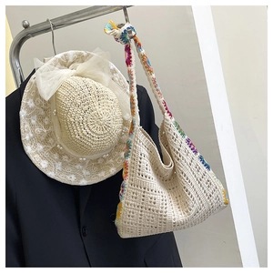 Detail of hollow crochet handbag with floral trim and pearl lace straw hat accessory
