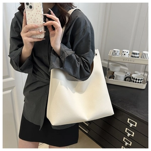 Lifestyle view of a large cream white pebbled leather hobo tote bag worn by a model