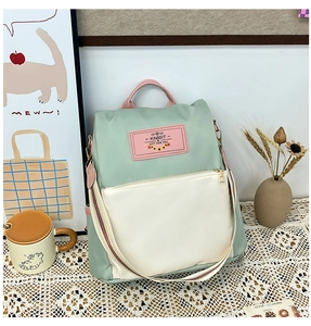 Detail of green and white nylon backpack with cute rabbit label and front zipper pocket