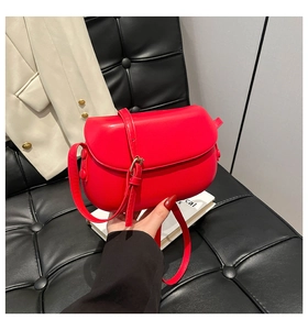 Close-up of vibrant red leather saddle bag featuring a smooth matte finish and adjustable strap