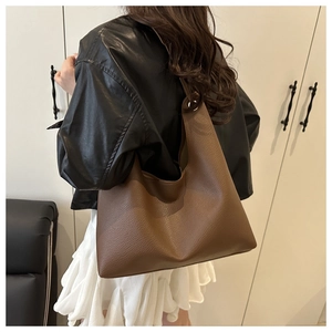 Brown lychee grain leather hobo bag worn with black jacket and white pleated skirt