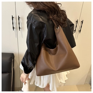 Detail of large brown lychee grain leather tote bag with silver metal ring and wide strap