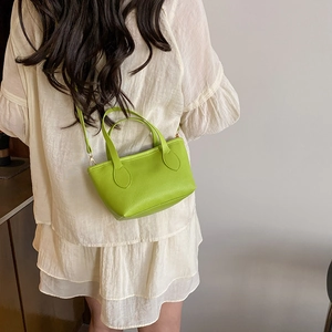 Bright green minimalist bucket bag with litchi texture shown on a female model