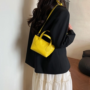 Vibrant yellow pebbled leather mini bucket bag with top handles and adjustable strap