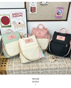 Detail showing four pastel nylon backpacks on a table with decorative tassel accessories