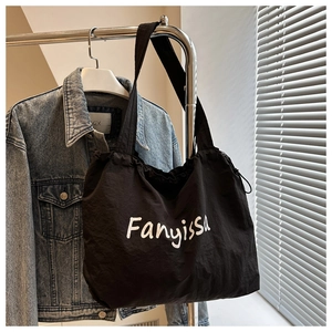 Detail view of a black nylon drawstring tote bag with white Fanyissa lettering