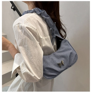 Detail of blue striped canvas bag featuring a silver butterfly buckle and pleated strap