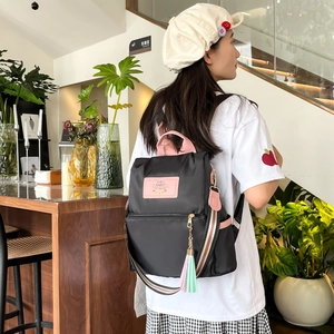 Black nylon backpack with pink accents and Rabbit label shown on a model in a cafe