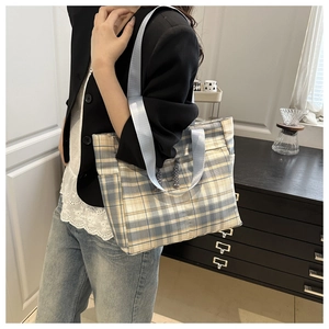 Close-up of stylish plaid tote bag with blue nylon straps on a casual lifestyle model