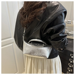 Detail of silver metallic dumpling bag with pleated texture on model in lifestyle setting