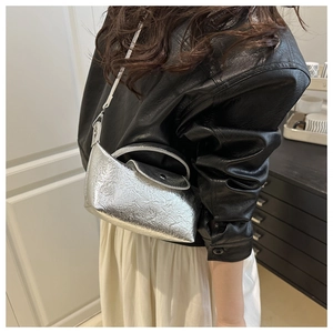Detail of silver metallic dumpling bag with pleated texture on black leather jacket