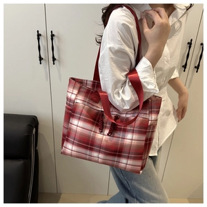 Detail of red British plaid tote bag featuring woven tassels and durable shoulder strap