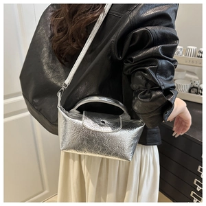 Detail of metallic silver crossbody bag with pleated texture on a fashion model