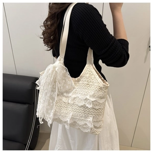 Détail du sac cabas en dentelle crème avec broderies délicates et anses en cuir