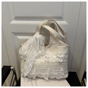 Vue détaillée du sac cabas en dentelle blanche à volants avec foulard en soie sur chaise