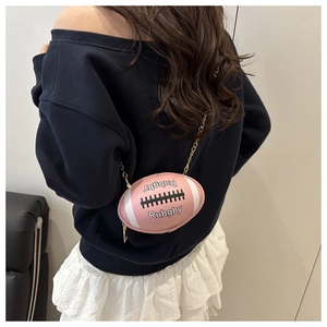 Pink rugby-shaped crossbody bag with gold chain strap worn by a model in casual outfit