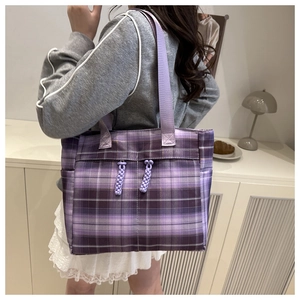 Detail of purple plaid canvas tote bag with woven straps and textured pattern