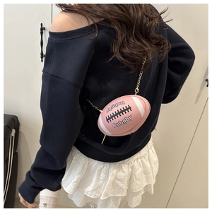 Rosafarbene Umhängetasche in Rugby-Form mit goldener Kette am Modell getragen