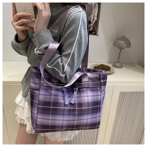 Detail of purple plaid tote bag showing woven knot zipper and durable fabric texture