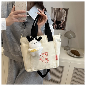 Detail of canvas tote bag with cartoon bear print and plush bunny keychain