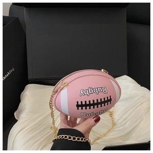 Detailed close-up of pink rugby-shaped crossbody bag with gold chain strap on satin