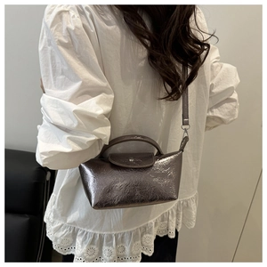 Detail of silver metallic dumpling bag with pleated texture on white shirt model