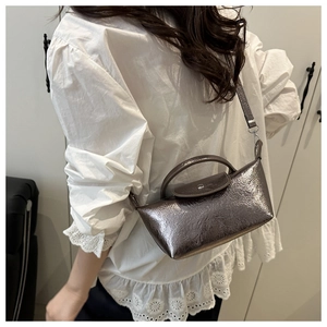 Detail of a metallic dark grey rectangular bag with a round buckle and long strap