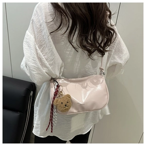 Détail du sac croissant en cuir verni rose clair avec breloque ours et ruban déco