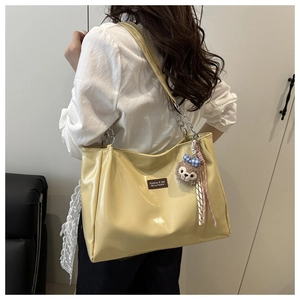Detail of yellow tote bag with glossy finish and stylish chain strap for women