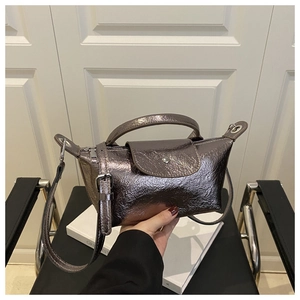Detail of metallic bronze dumpling bag with shiny pleated texture and top handle
