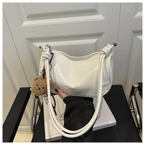 Détail du sac demi-lune plissé blanc avec breloque ours et texture en similicuir