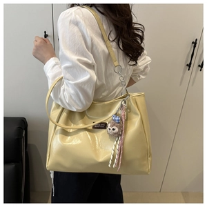 Detail of cream tote bag with glossy finish and cute plush animal charm accessory