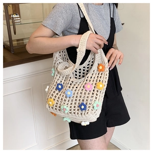 Detail of a handmade crochet flower mesh bag with colorful 3D floral accents on a cream base