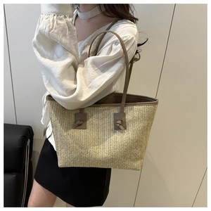 Detail of hand-woven straw tote with brown leather handles and decorative knots