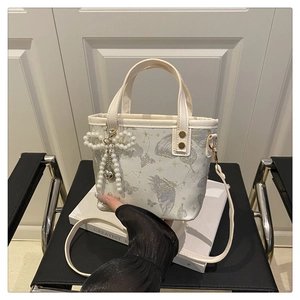 Close-up of white bucket bag with purple butterfly prints and pearl bow charm detail