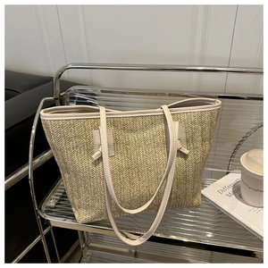 Detail of woven straw tote bag with cream leather handles on a modern silver shelf