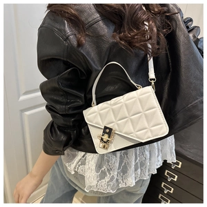 Close-up of a white quilted crossbody bag with gold-tone hardware and chain detail