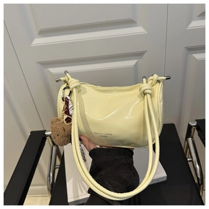 Détail du sac bandoulière en cuir jaune clair avec pendentif ours et sangle nouée