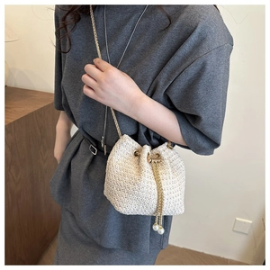 Detail of white woven bucket bag with pearl tassels and golden drawstring hardware
