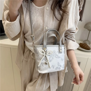 Elegant bucket bag with butterfly print and pearl bow detail in a cozy home setting