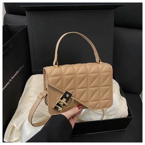 Detail of camel quilted square bag with gold lock in elegant gift packaging