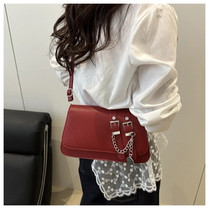 Detail of red crossbody flap bag with silver chain and dual buckle straps on a model