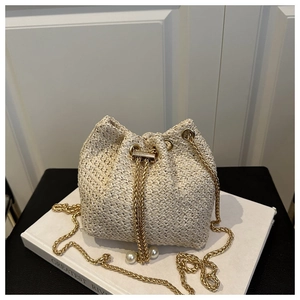 Detail of off-white woven straw bucket bag with gold chain strap and pearl drawstring