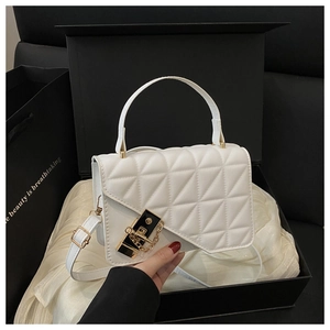 Close-up of white quilted square bag with gold twist lock and elegant chain strap detail