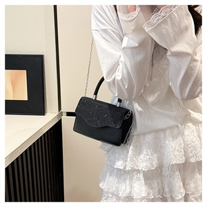 Close-up of a black sequined flap mini chain bag paired with a white lace dress