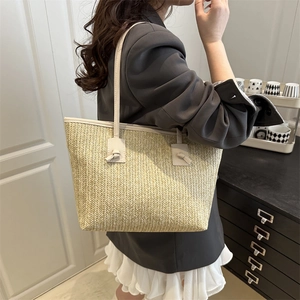 Chic woven tote bag in beige straw finish with elegant knotted shoulder strap detail