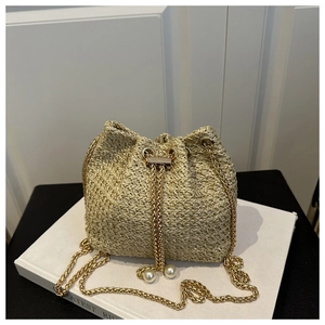 Detail of straw bucket bag featuring pearl drawstring and gold metal chain strap