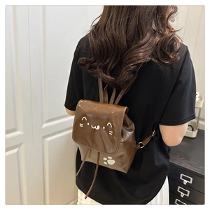 Detailed view of the dark brown mini backpack featuring a glossy cat-themed cartoon design