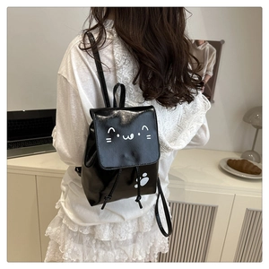 Detail of a black glossy mini backpack with cat face print and drawstring closure