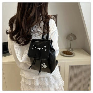Detail showing mini black glossy backpack with cute white cat face and paw print